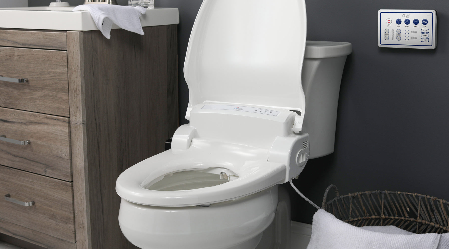 A BB-1000 Supreme bidet seat with the lid up. It's installed on a toilet in a gray-walled bathroom.