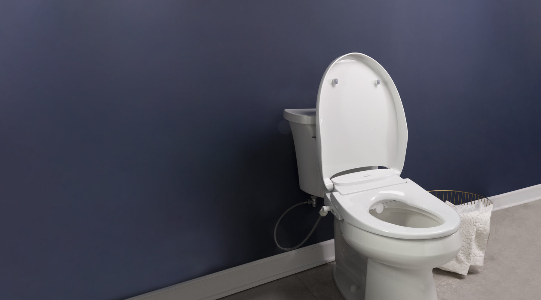 A Discovery DLS bidet seat installed, seat up, on a toilet in a navy blue bathroom.