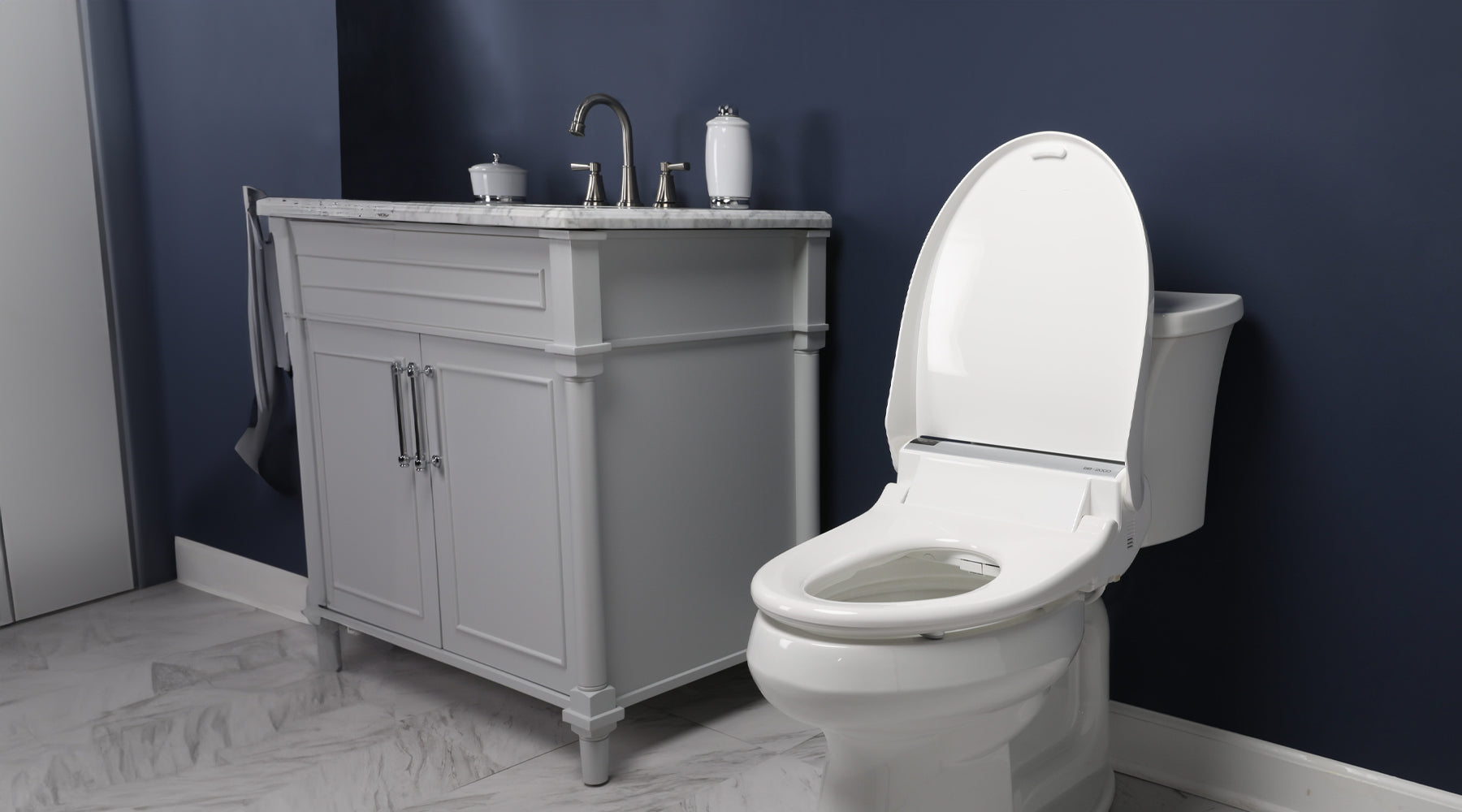 A two-piece toilet in a navy bathroom with the Bliss Bidet toilet set installed.